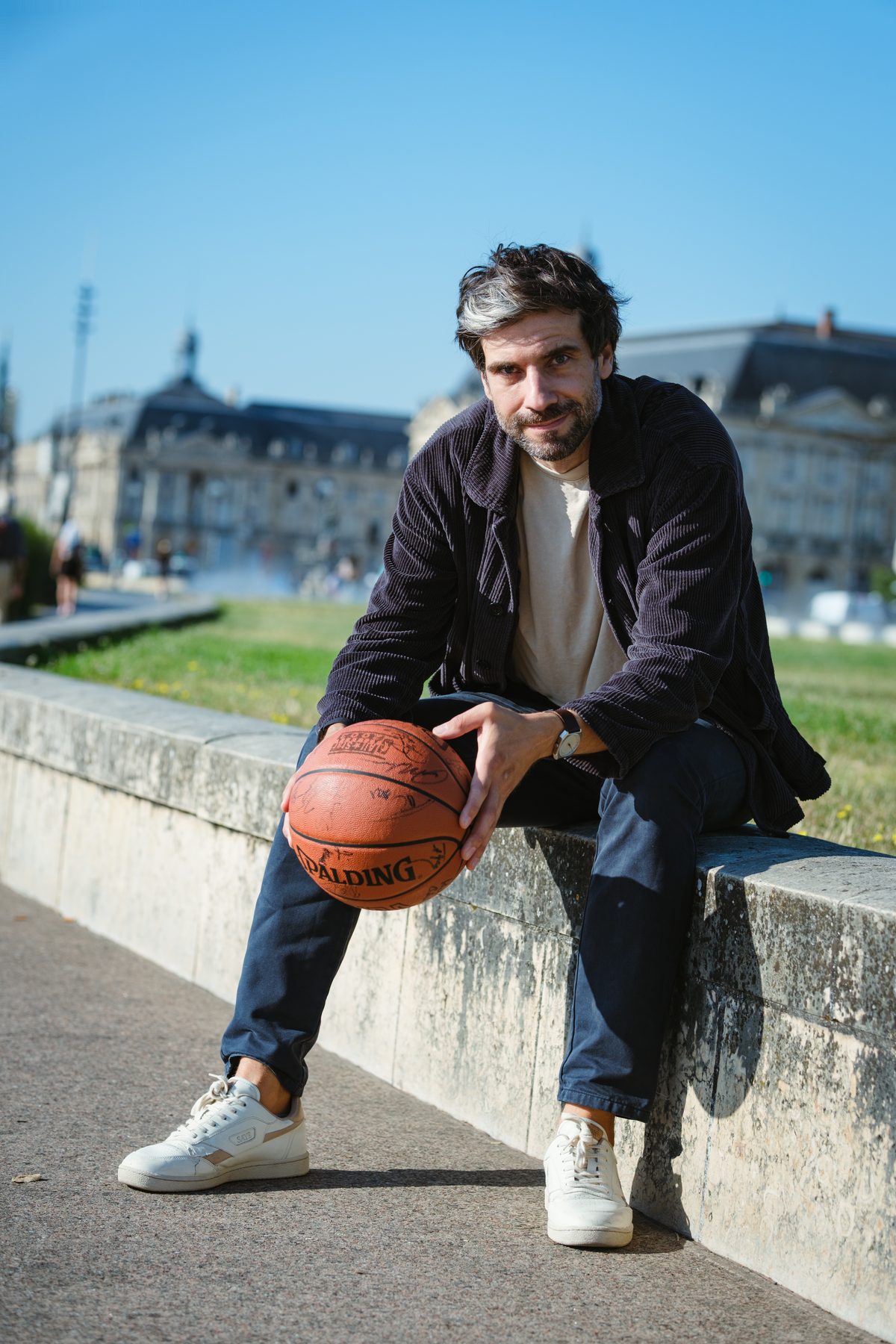 Gauthier Helloco assis sur les quais de Bordeaux, ballon de basket sur les genoux